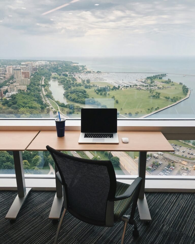 A laptop laying on table with office chair